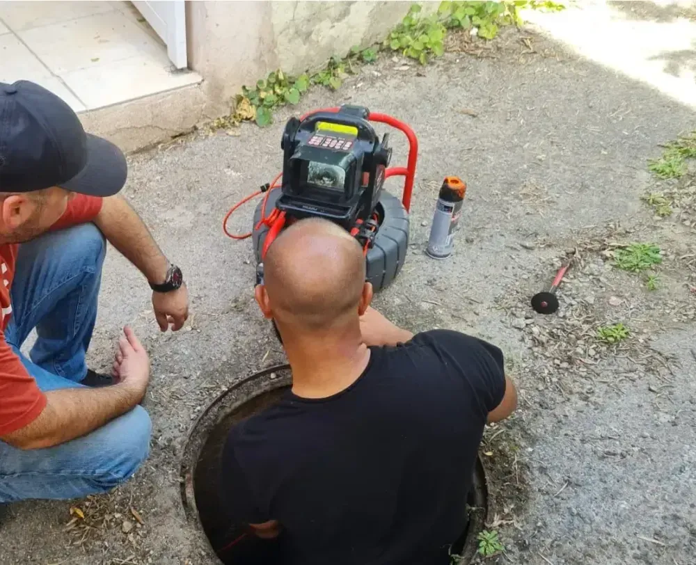 Technicien plombier réalisant une inspection vidéo de canalisation dans un immeuble moderne à Annemasse